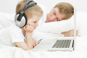 child in headsets with computer while father is asleep, family leisure